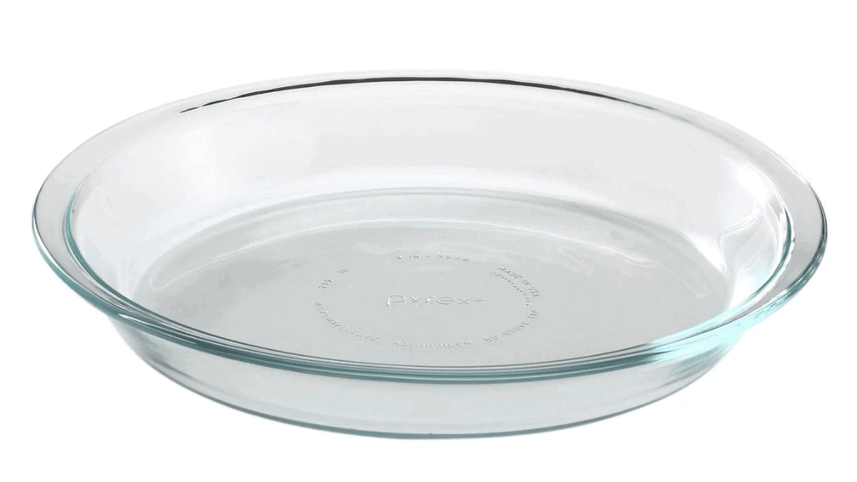 A glass pie dish is placed on the white and plain surface. 