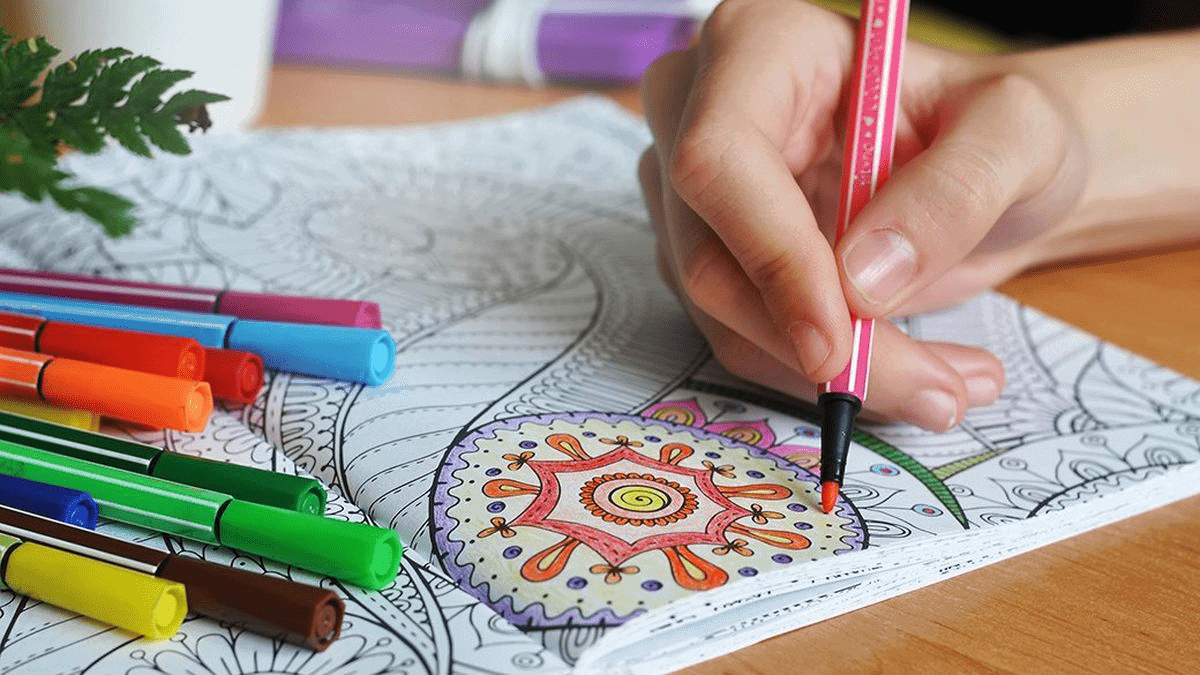 An Adult coloring a mandala with sketch pens. 