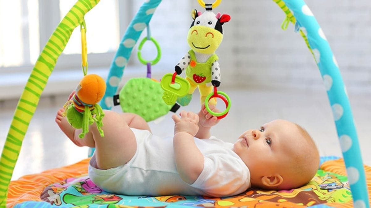 a baby playing with the Baby gym set. 