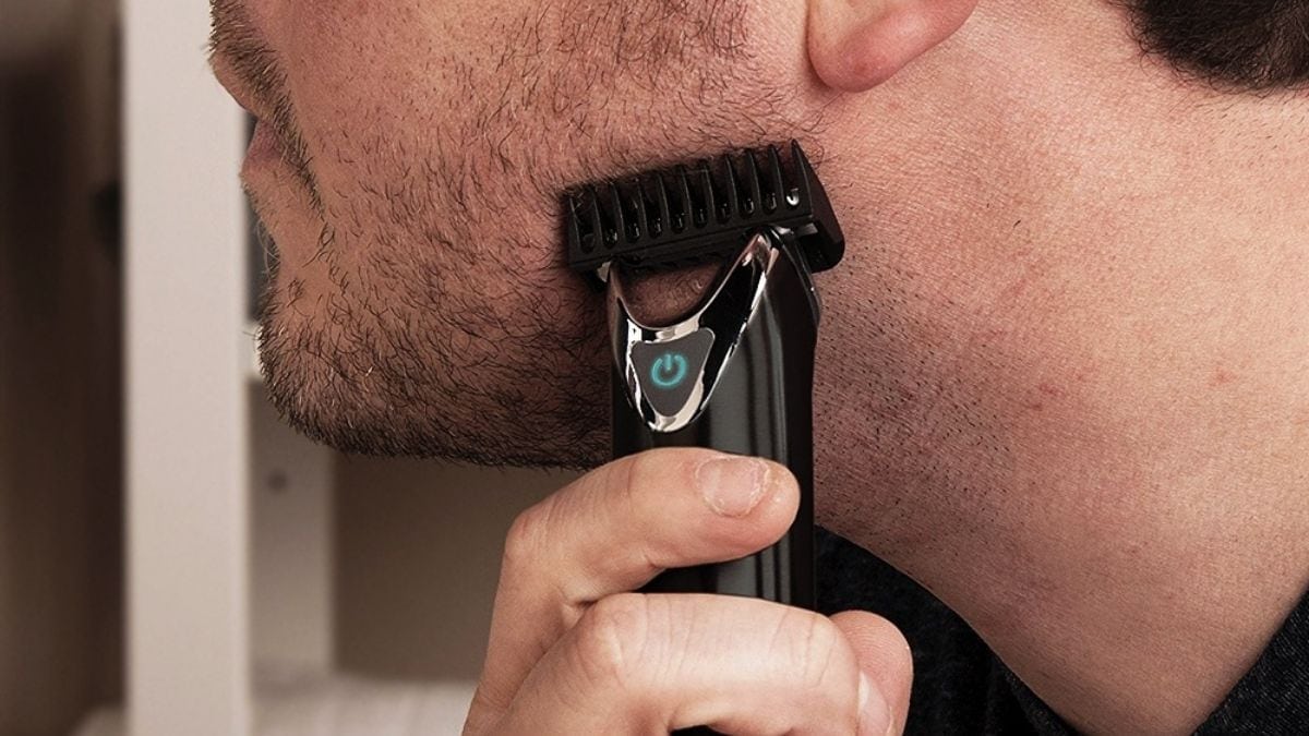 A guy trimming his beard with a trimmer