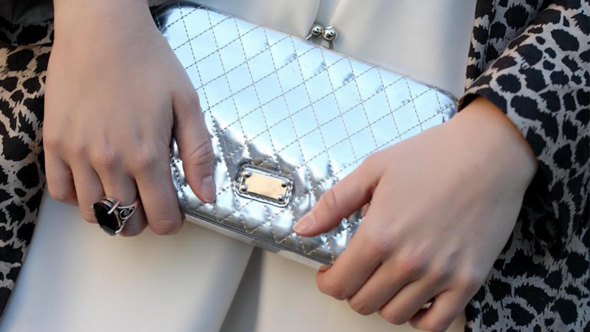 a woman holing a shining silver clutch in her hands