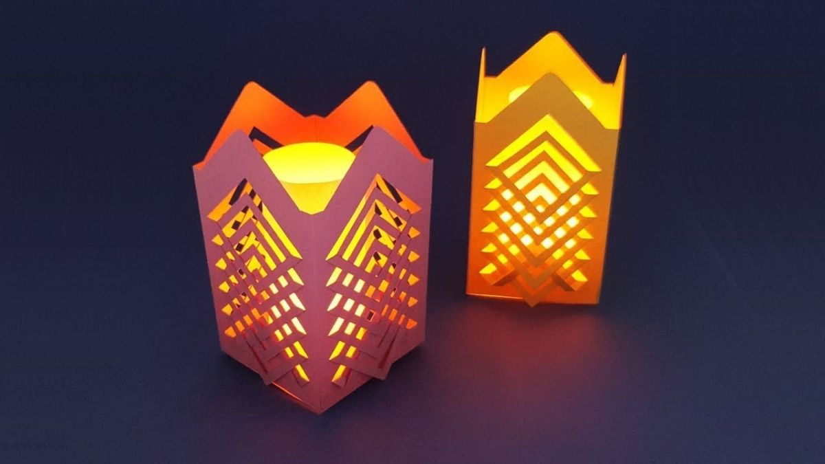Two handmade lanterns are placed on a plain surface.