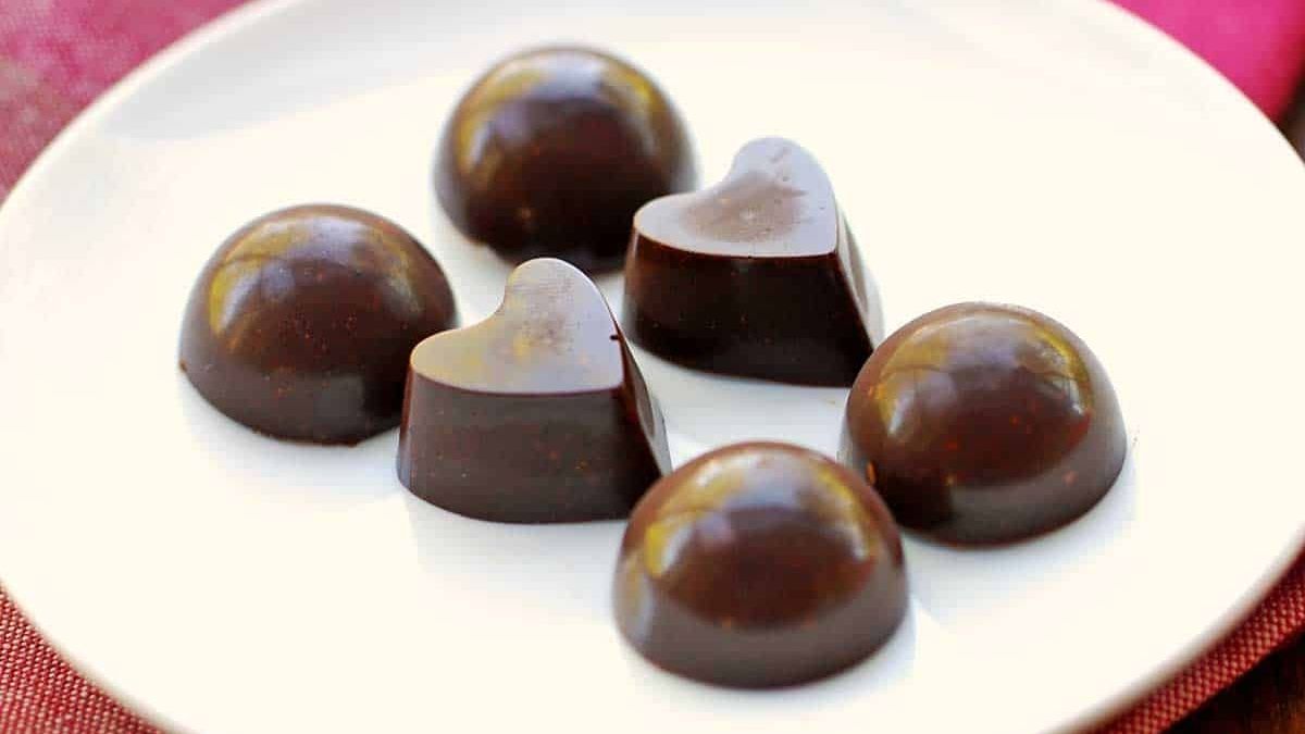 Two heart-shaped and rounded chocolates are placed on the white plate. 