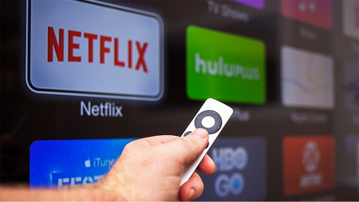 OTT platforms like Netflix, Hulu, HBO falshing on screen while  a person hold a remote controller. 