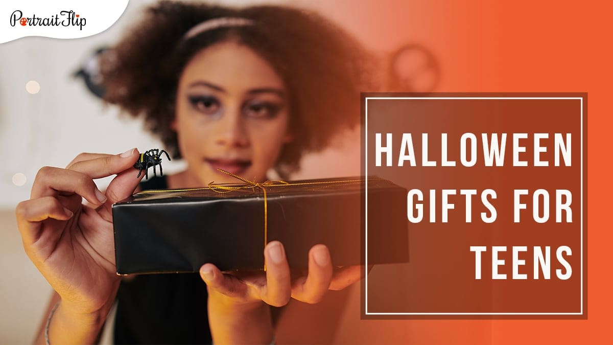a teenager with puffed hair and spooky makeup holding a toy spider on top of a black gift with golden ribbon with Halloween Gifts for Teens written on a block on the right hand side