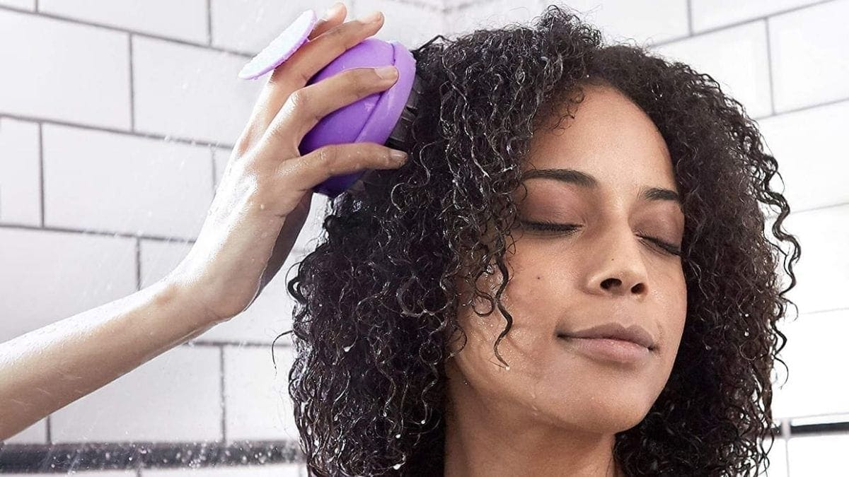 a woman massaging her scalp with a scalp massager. 