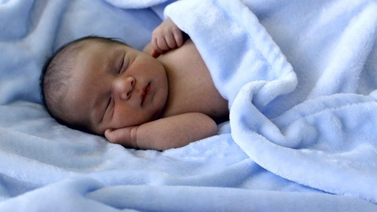 a baby sleeping in a soft blue colored blanket. 