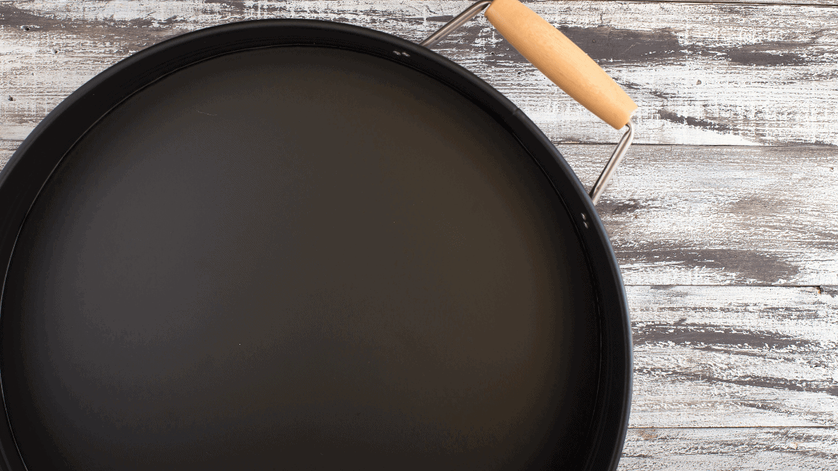 A black colored pizza baking pan on the grey surface.  