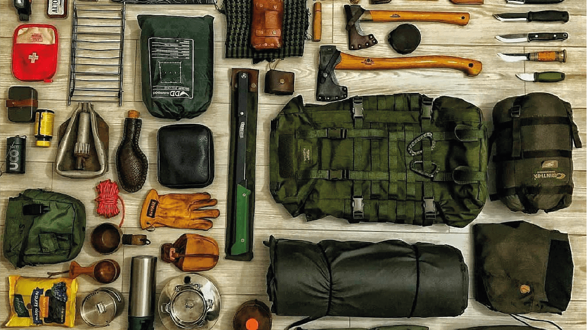 various survival tools including hammer, knives, bagpack, gloves etc are kept on the table