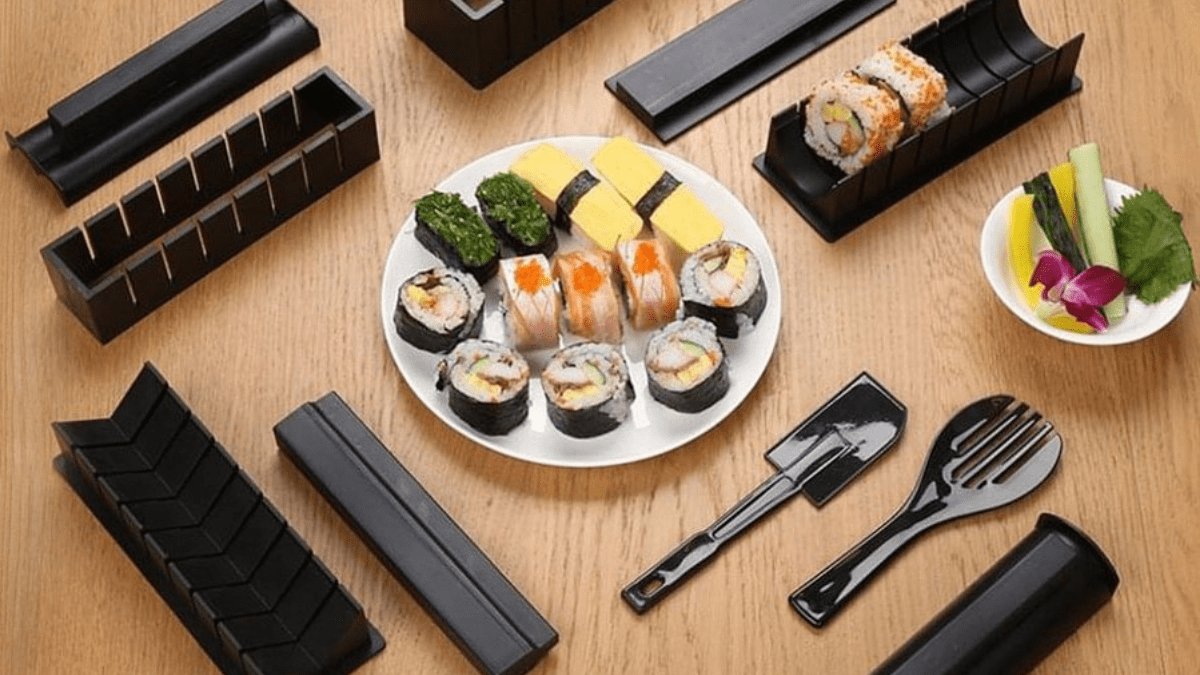Sushi making kit and some delicious Sushi is being served on a white plate placed on the wooden surface. 