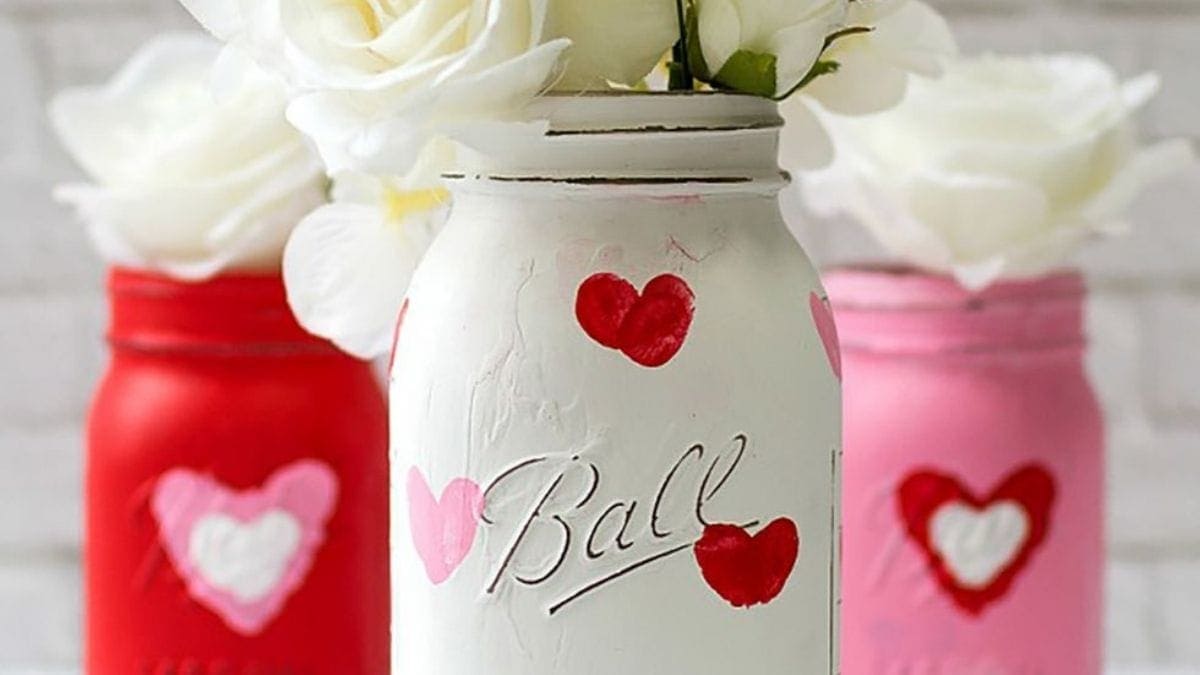 A white colored beautiful jar is placed ahead of two jars which is embellished with pink paper. 