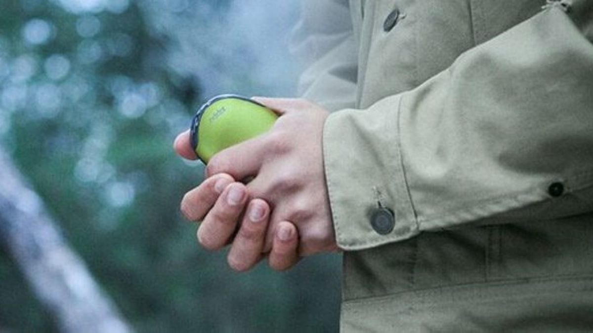 a person holding an USB hand warmer in the cold.