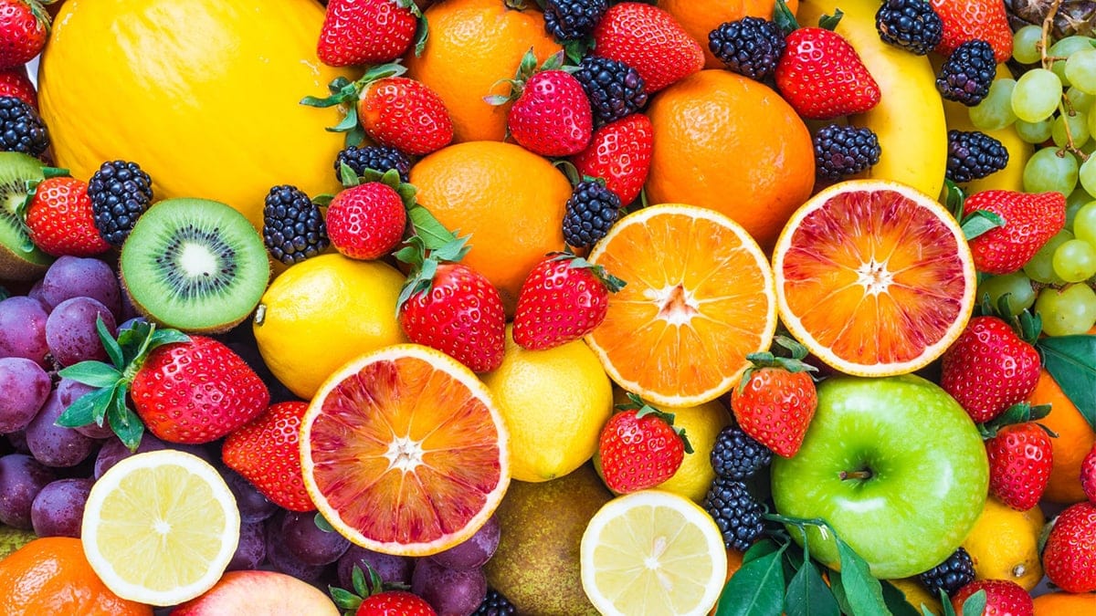A photo of fruits from above: oranges, mulberry, strawberry, apple, lime, grapes, banana, kiwi