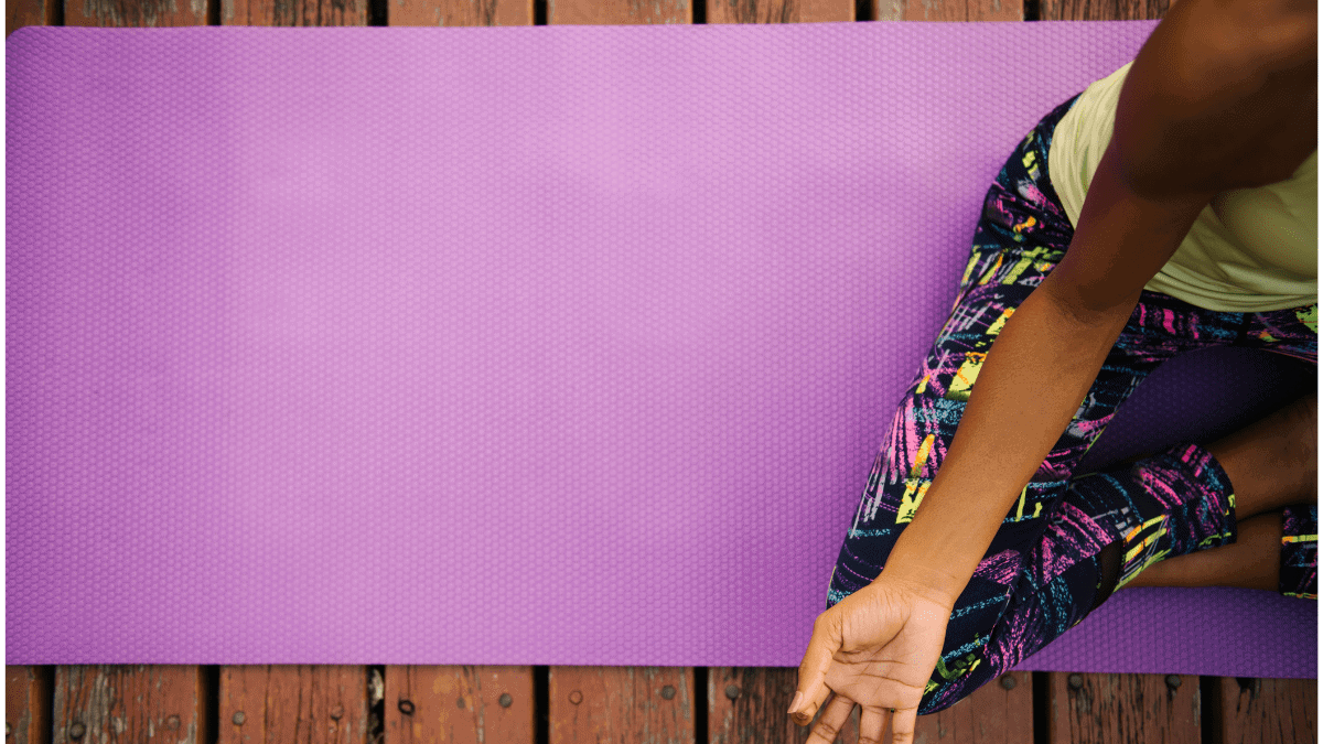 A girl doing yoga on a purple yoga mat 