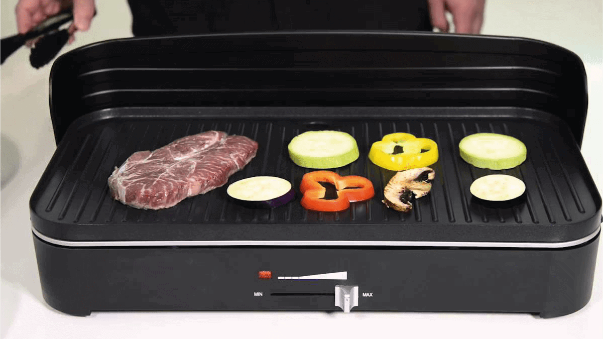 a piece of meat and veggies are getting grilled on an electric griller. 