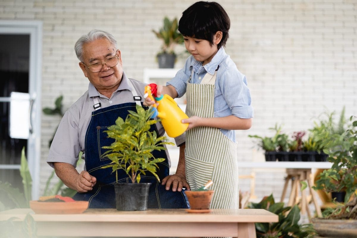 A grandpa is teaching his grandchild how to garden and water the plants with his personalized watering can.
A personalized watering can makes for a good Christmas gift. 