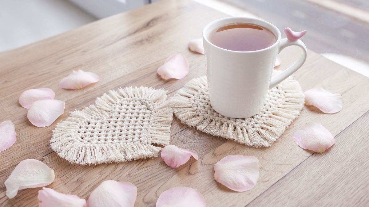 Two heart-shaped handmade coasters are placed below a glass of tea. 