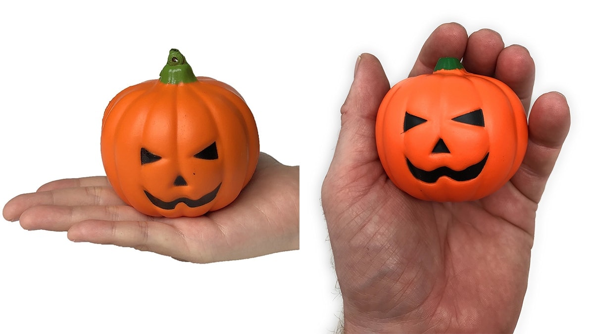 2 hands holding a pumpkin shaped stress ball each, a gift that can be given to coworkers on Halloween.