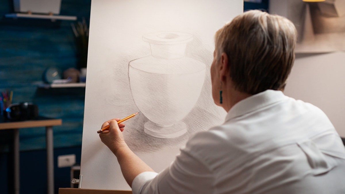 An artist drawing her painting's outline on a canvas. 