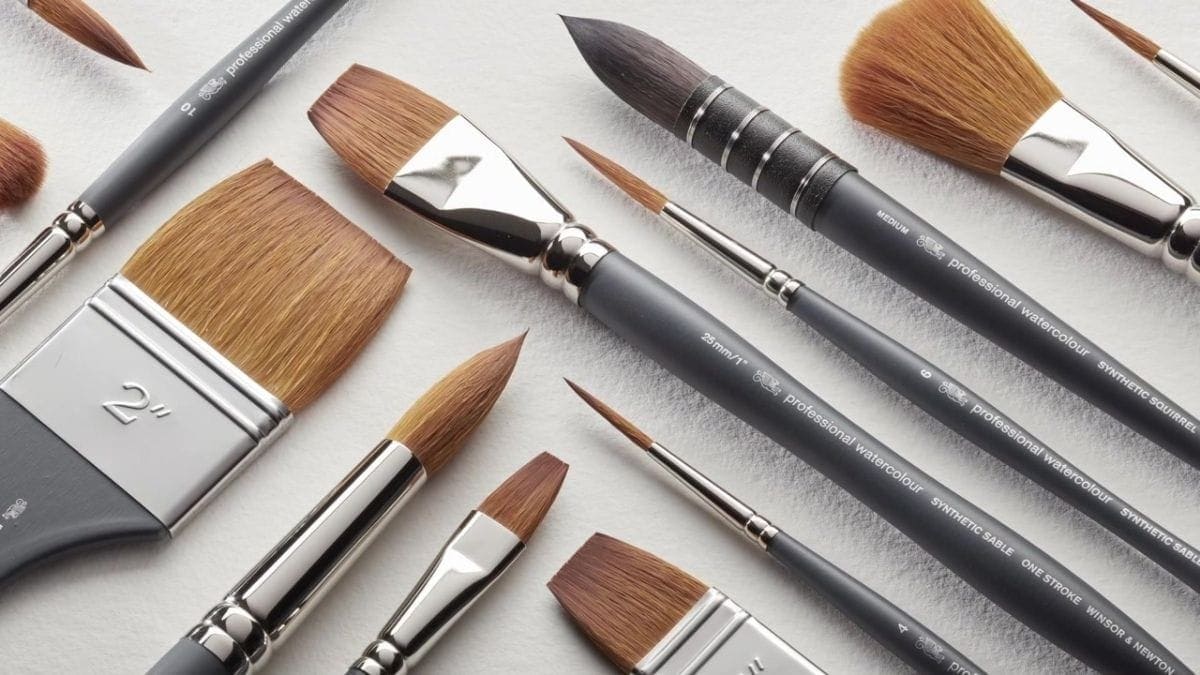 Different types of watercolor paint brushes on a white table. 