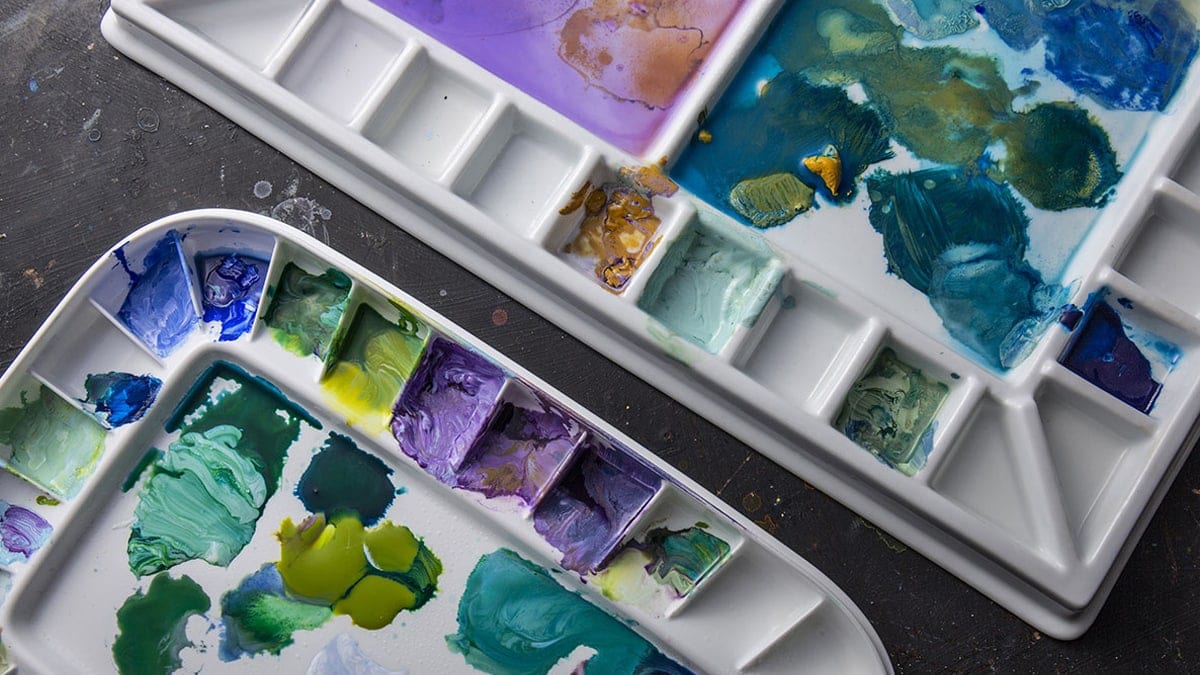 dirty acrylic painting palettes with different colors of acrylic paints.