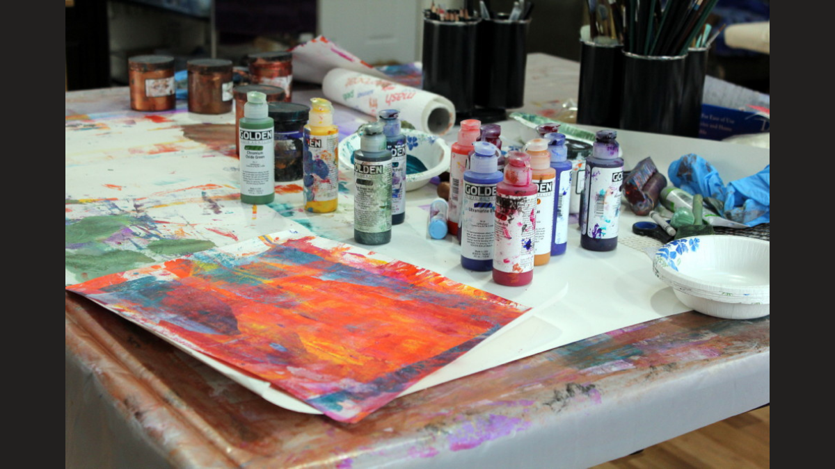 a dirty table is shown with colors and canvases before being cleaned.