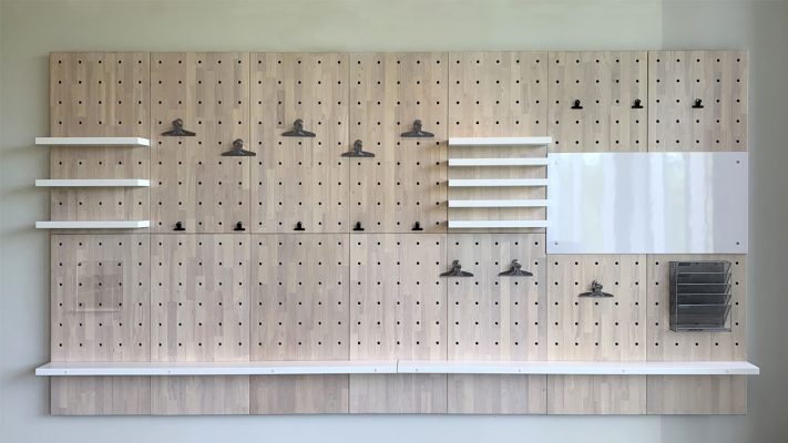 A pegboard is installed on the wall of a a entryway. 