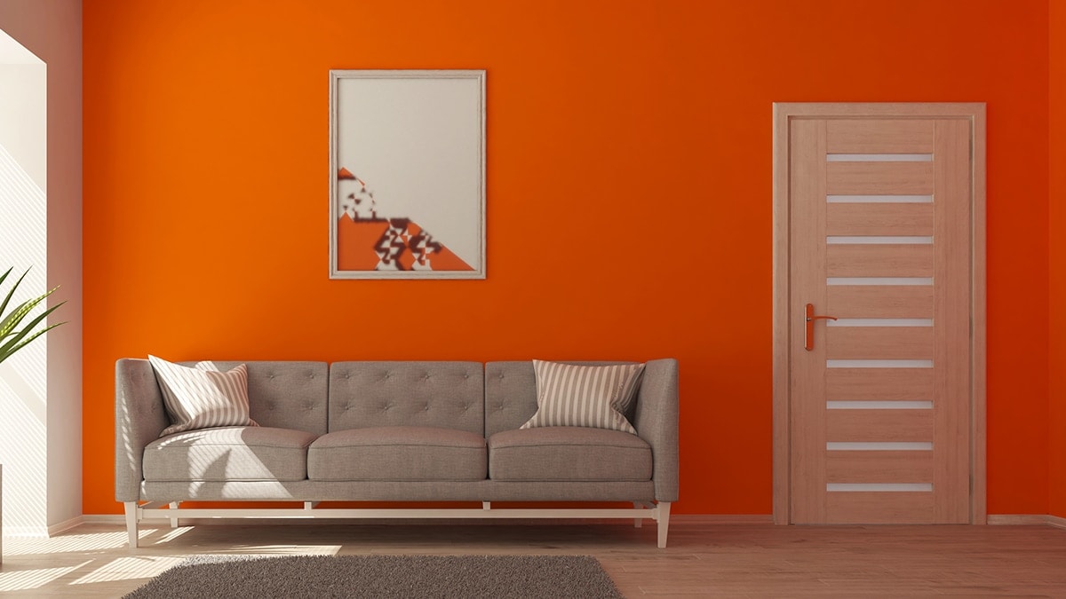 A home decor painting is on the orange wall.. 