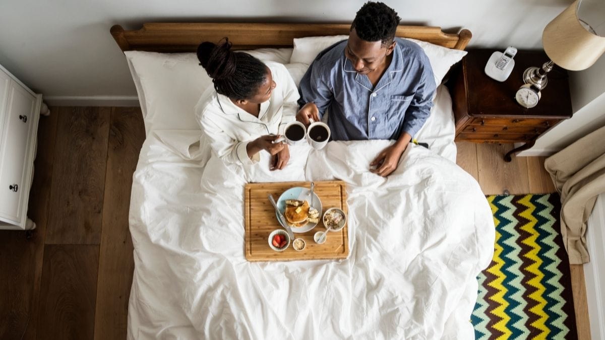 A couple is enjoying their valentines day by having breakfast in bed. 