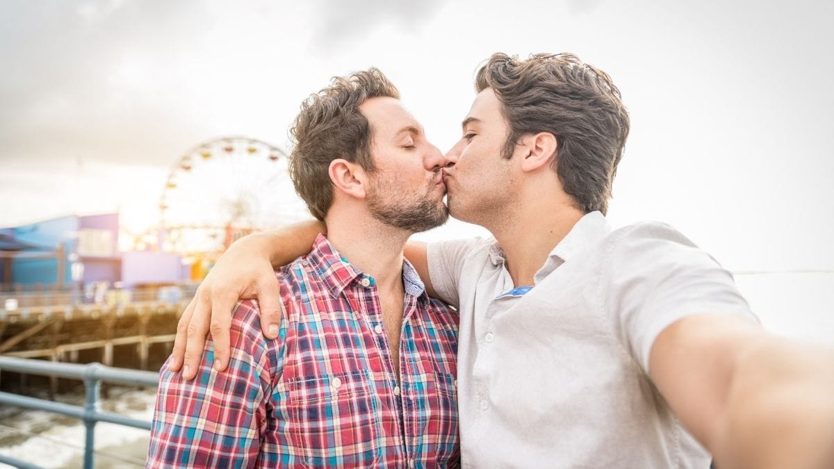 A Gay couple sharing a kiss in front of a theme park where they had their first date. 