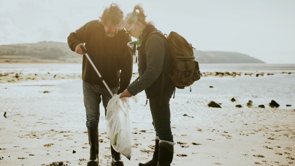 An elderly couple volunteering to clean up a beach near their house.
 