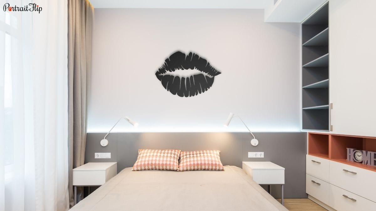 a metal wall décor in the shape of plump lips hanging in a bedroom.