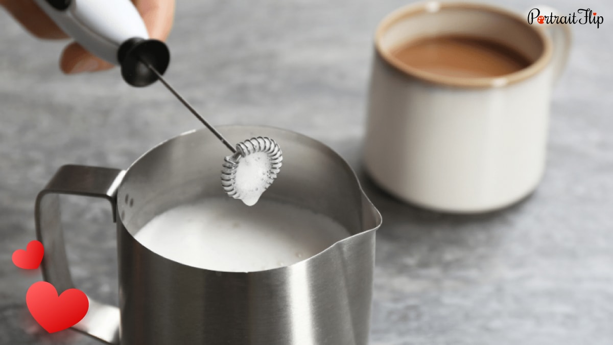 a mini frother frothing the milk and beside is a cup with coffee. 