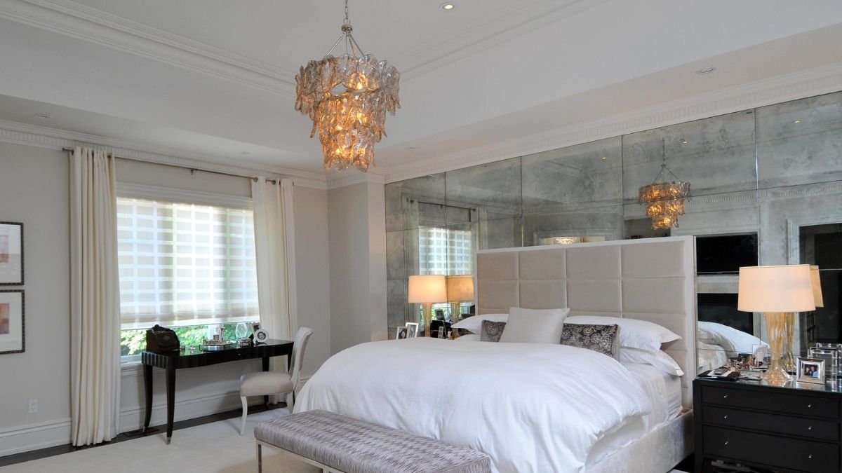 a beautiful bedroom interior with an entire mirrored wall shown as a bedroom wall decor idea.