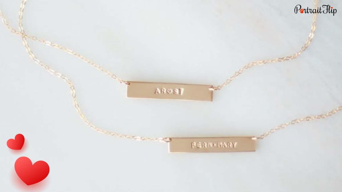 2 golden colored Personalized bar necklace with names on it. 
