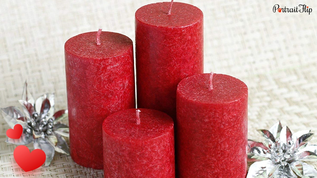 4 red colored valentine's day candles are kept on a mat. 
