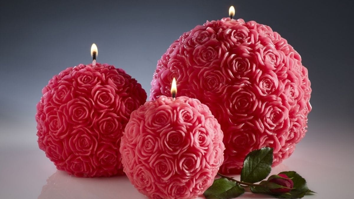 three round rose candles are lit on a table. 