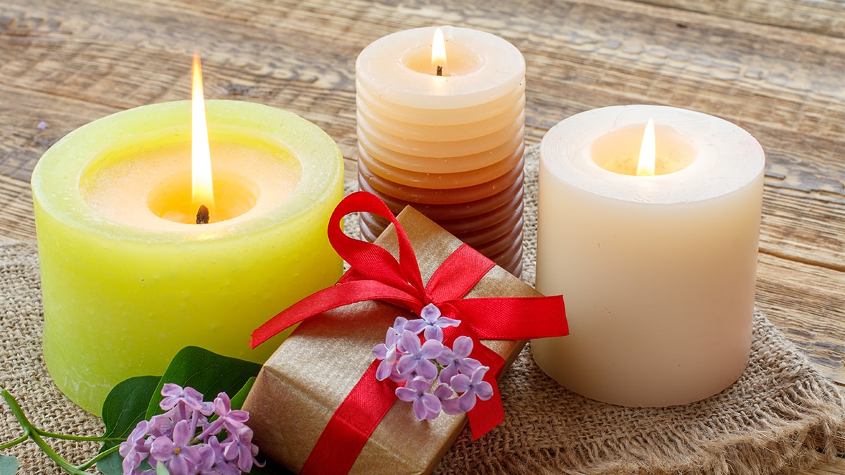 Different scented candles palaced along with a small gift on a brown table