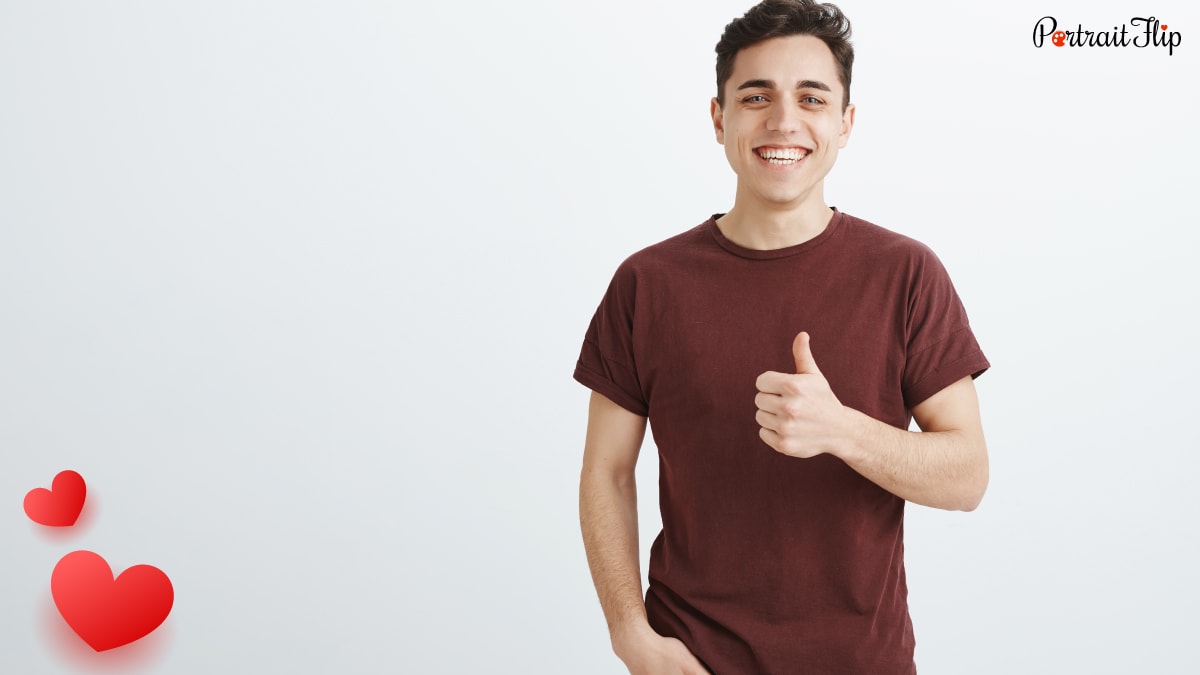A smiling man wearing a brown t-shirt giving a thumbs up 