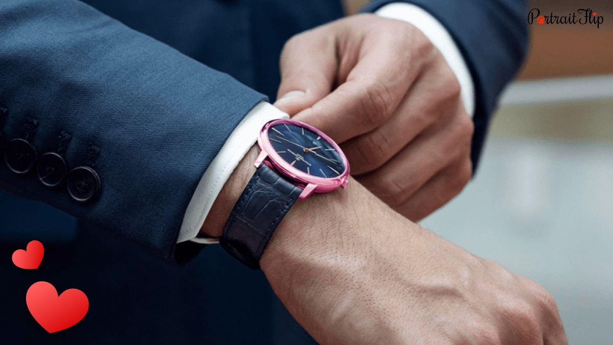 A closeup shot of a pink colored timepiece on a man's hand. 