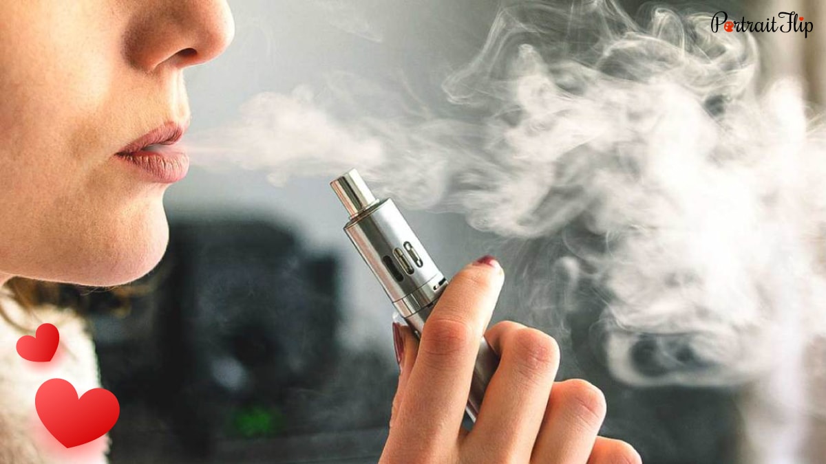 A woman blowing  smoke while holding a Vape in her hand.