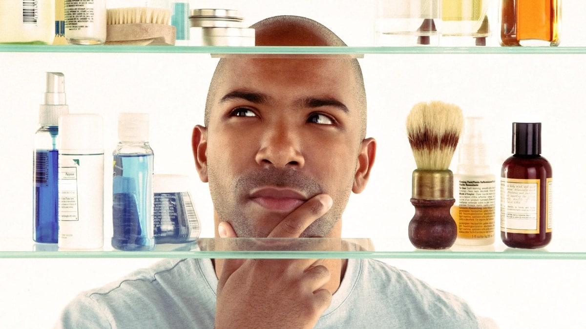There are shelves with grooming items on them and there is a man with a hand on his face and is in a thinking position. This is one of the graduation gift ideas for boyfriends,