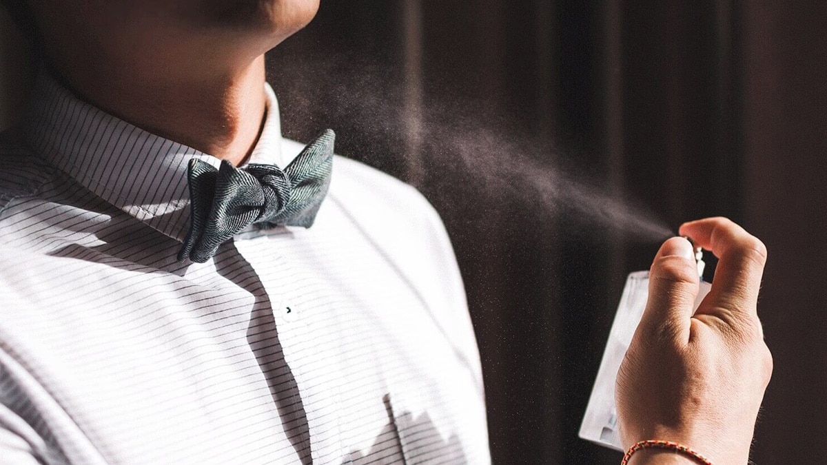 The image shows a guy spraying perfume on himself. Perfume is one of the other graduation gift ideas for boyfriends.