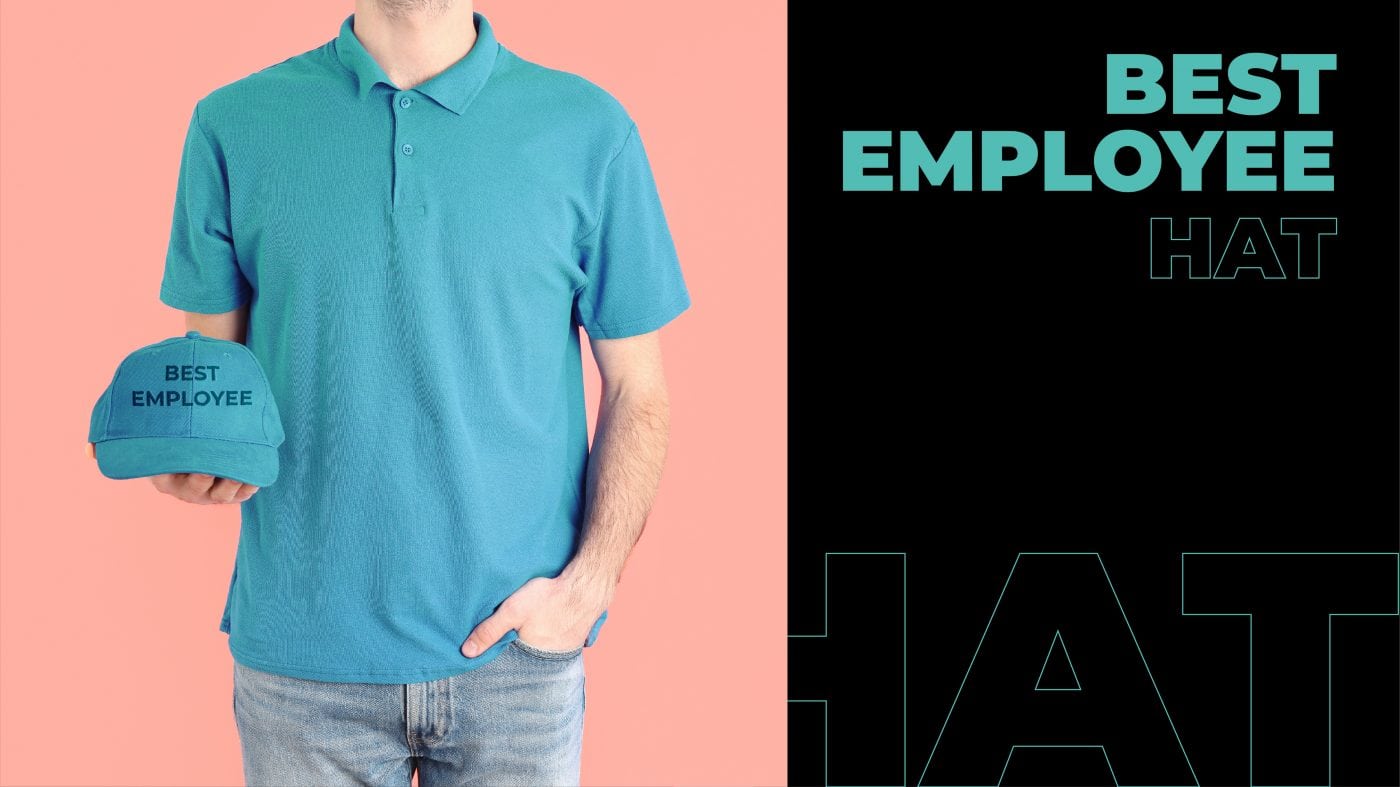 A man wearing a turquoise t-shirt holds   a "Best Employee" hat. 