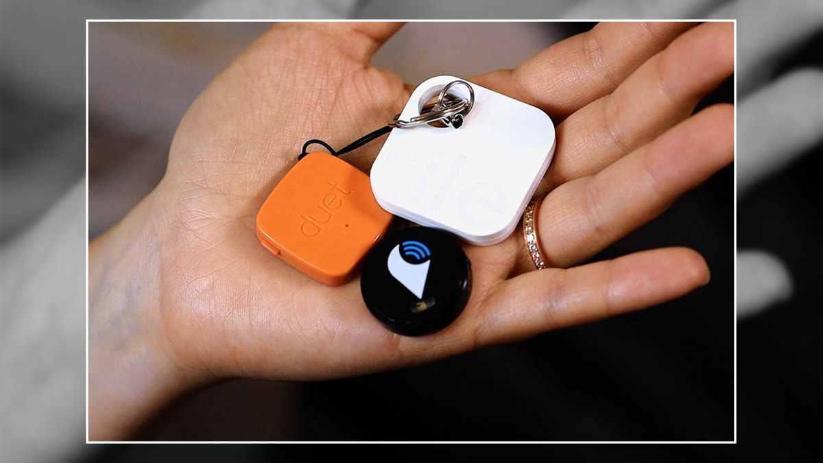 a hand holding three different Bluetooth tags