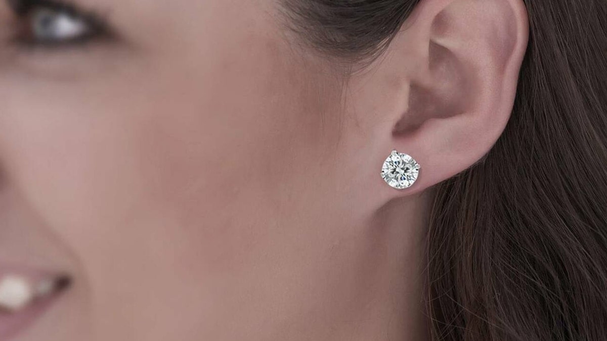 A girl wearing diamond stud earrings and smiling, another graduation gift for her.