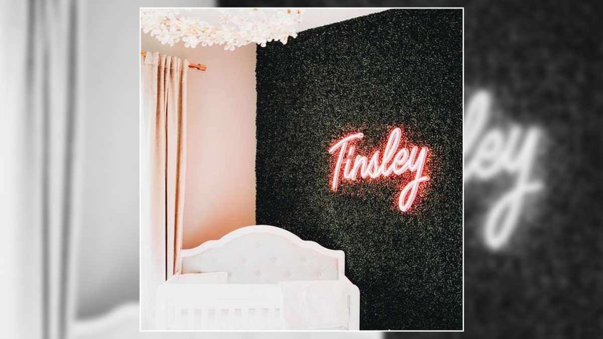 A neon name sign on a wall in a room. One of the graduation gift ideas for d`aughter.