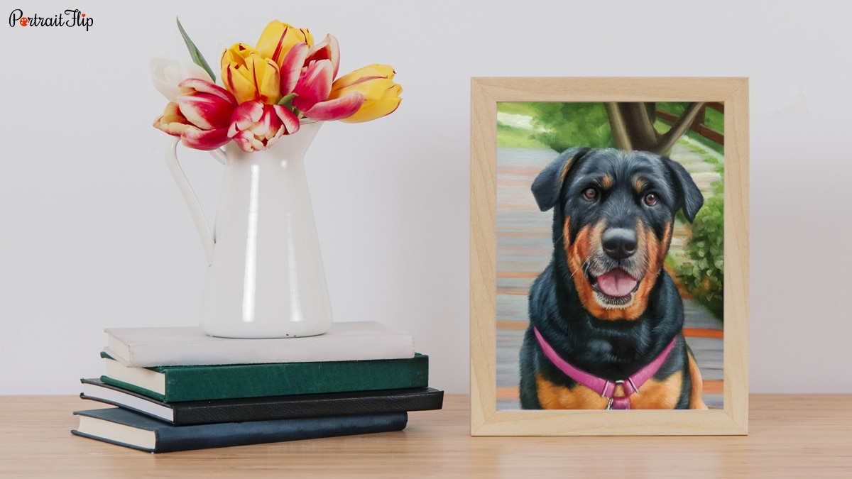 a painting of a dog that is painted by portraitflip's artist is placed on a study table beside a few books and flower pot, 