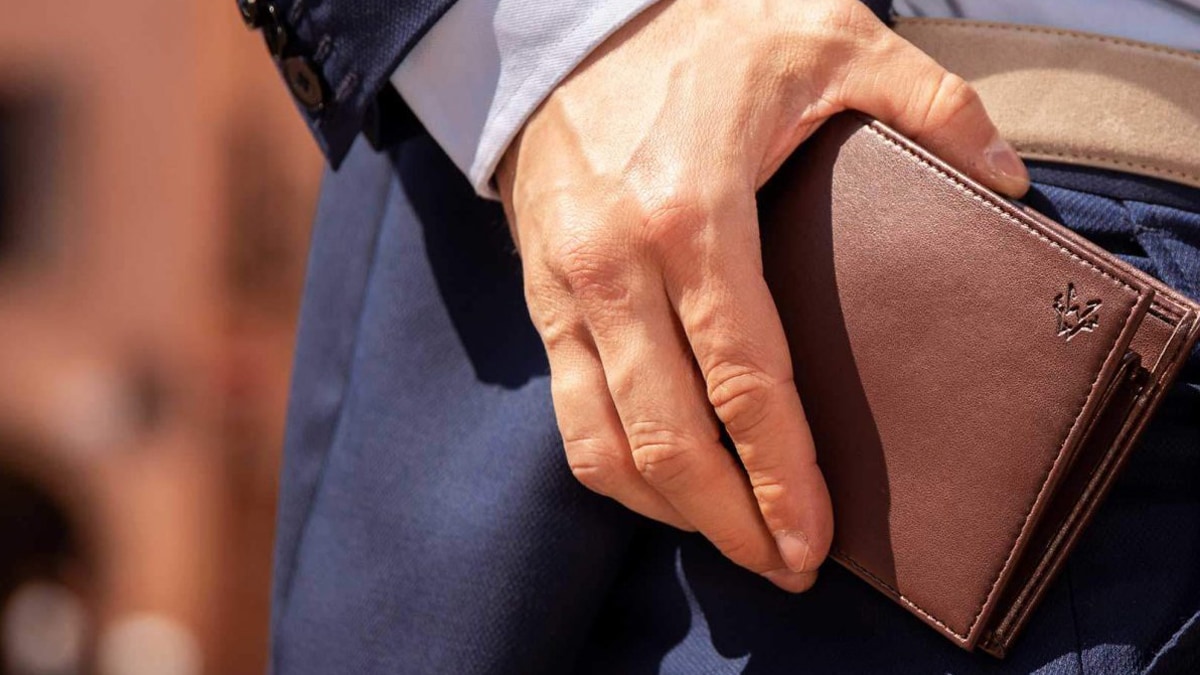 An image of a guy holding a wallet in his hand and sliding it in his pockets. This is one of the other graduation gift ideas for boyfriends.