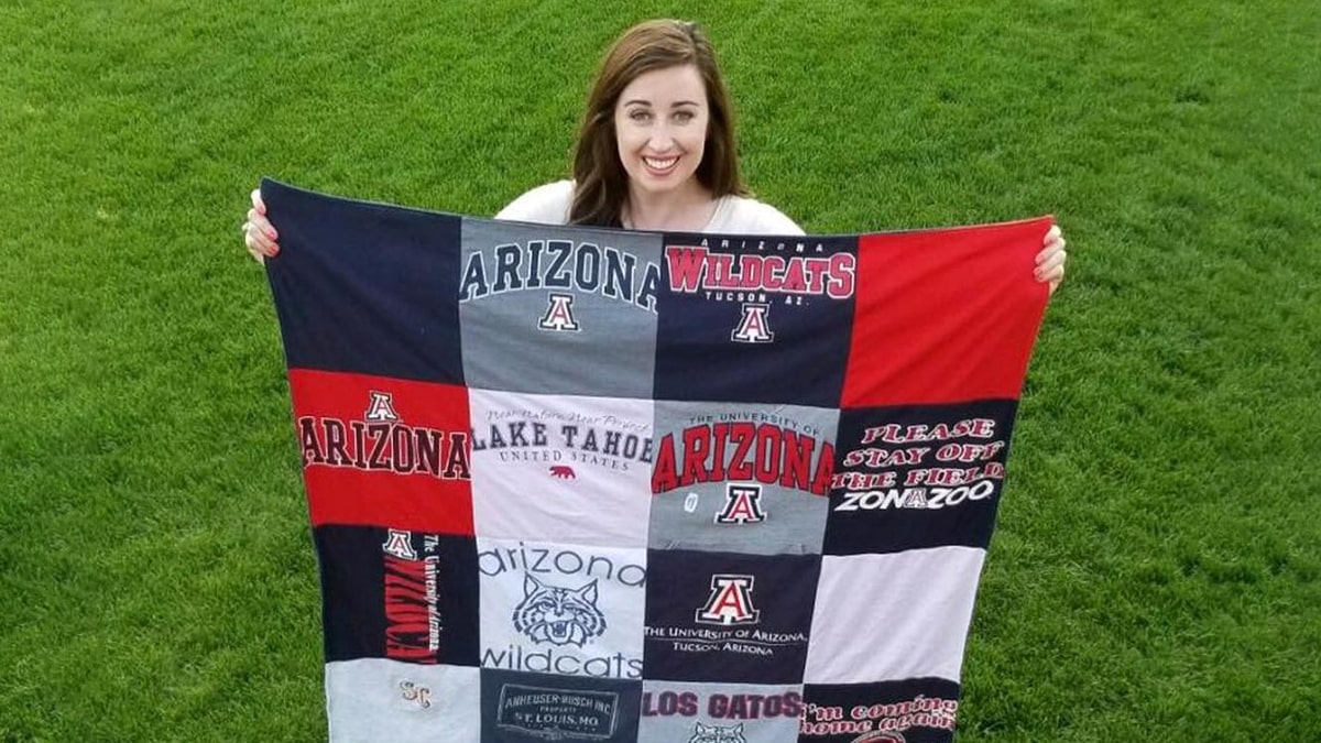 A lady holding a quilt made of all of her fav clothes, this is one of the graduation gift ideas for daughters.